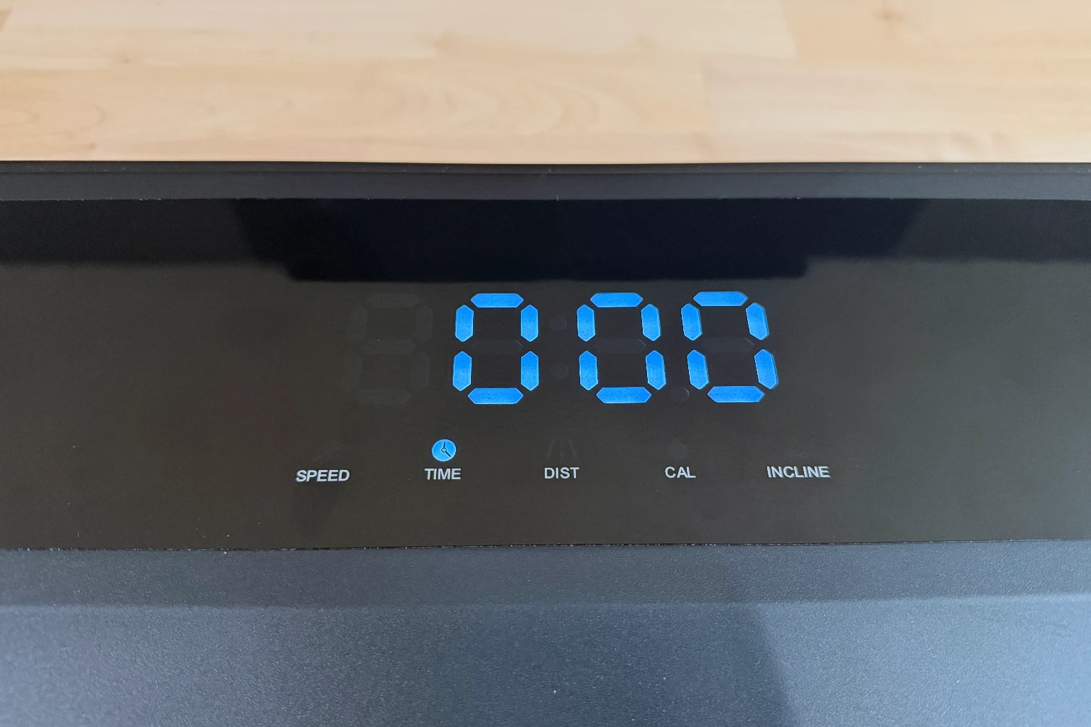 Close-up of the blue LED display on the UPLIFT Inclining Walking Pad showing a speed of 0.60 mph