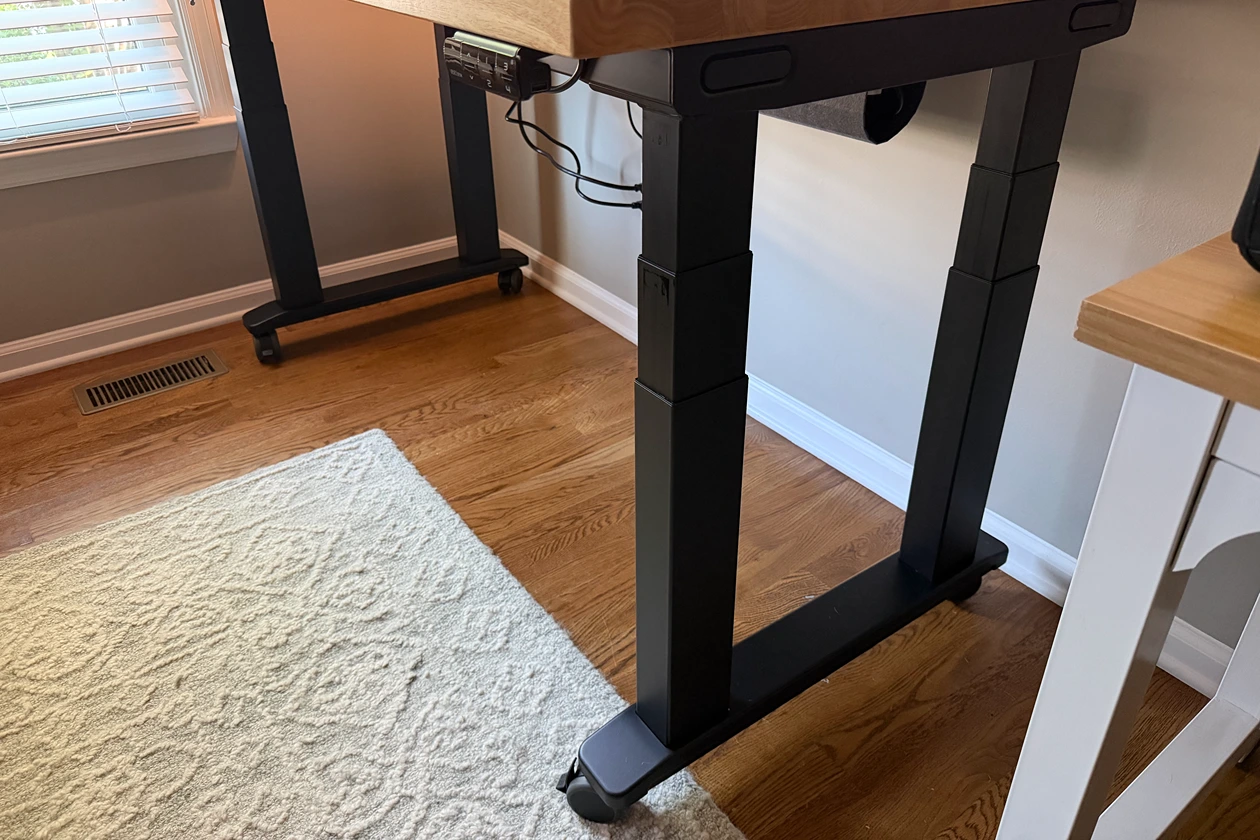 Low-angle view of the four lifting columns beneath the UPLIFT V3 4-Leg Standing Desk