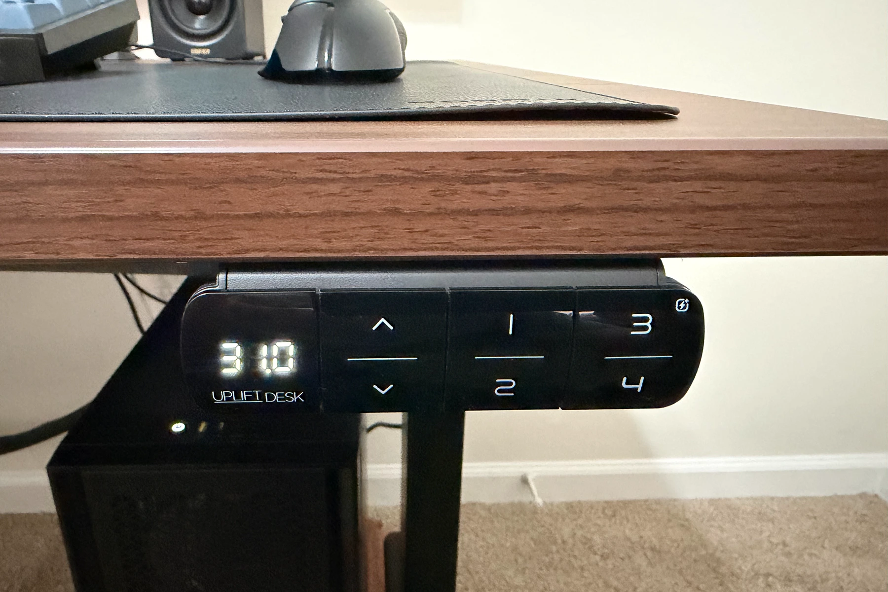 The UPLIFT V3 standing desk keypad mounted along the front edge of the desktop