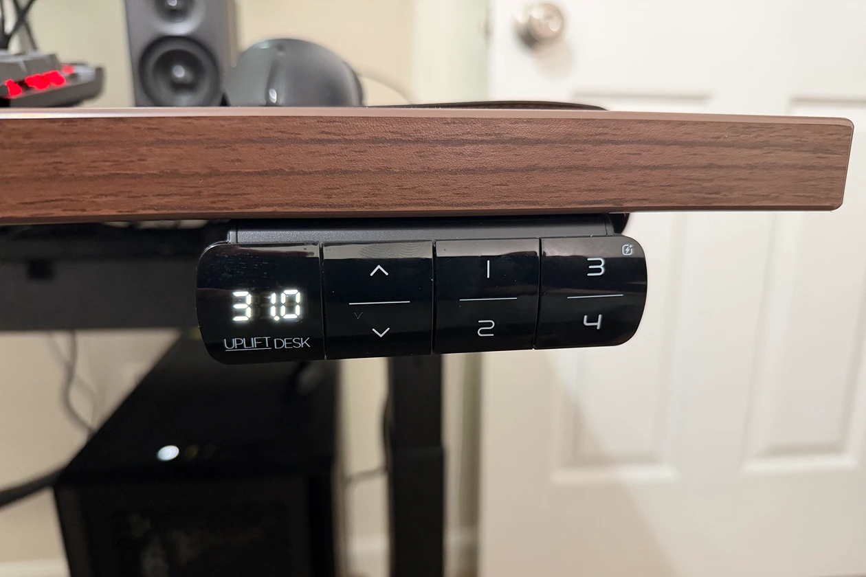 The UPLIFT V3 standing desk keypad mounted along the front edge of the desktop